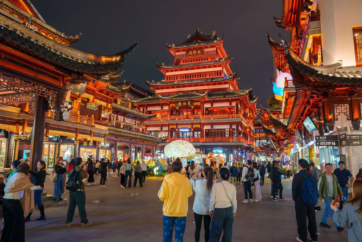 Traditional Chinese temple buildings illuminated at night with red lanterns and ornate architecture.