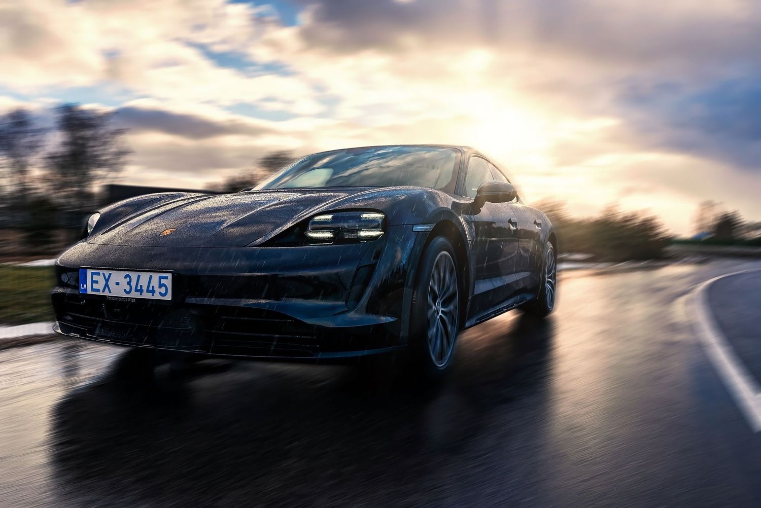 Silhouette of Porsche Taycan electric sports car against golden sunset.