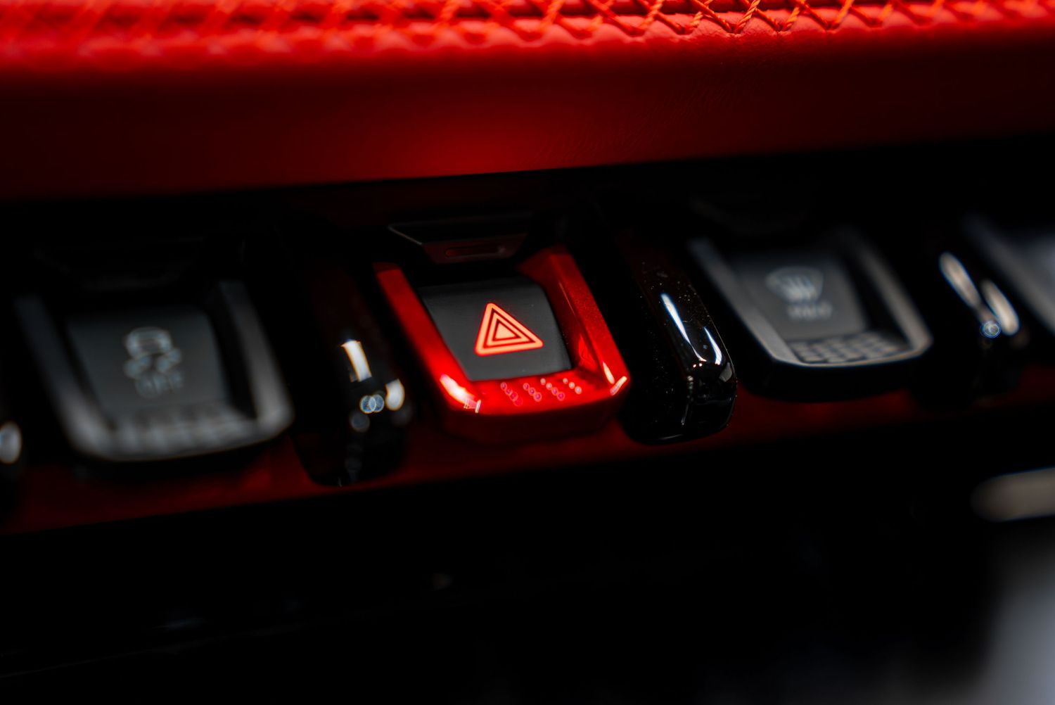 Hazard light button with red illumination among vehicle control switches.