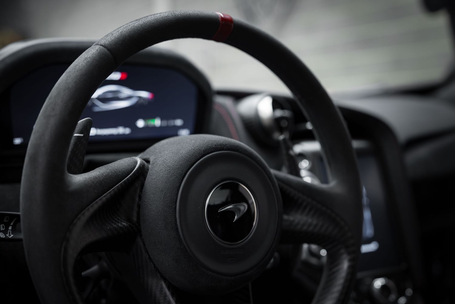 Close-up of a McLaren steering wheel and digital dashboard display.