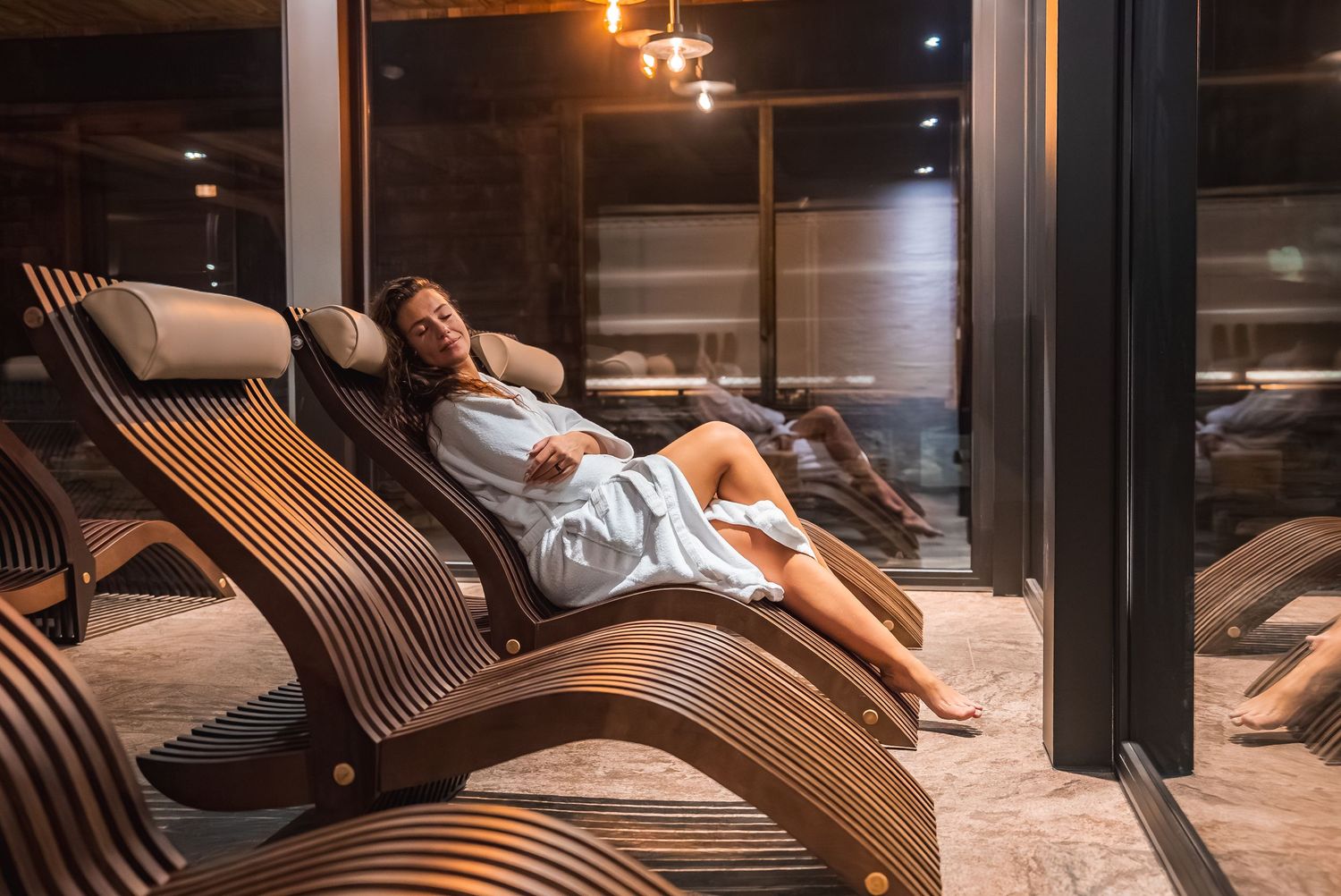 Relaxation area with curved wooden loungers in a dimly lit spa setting.