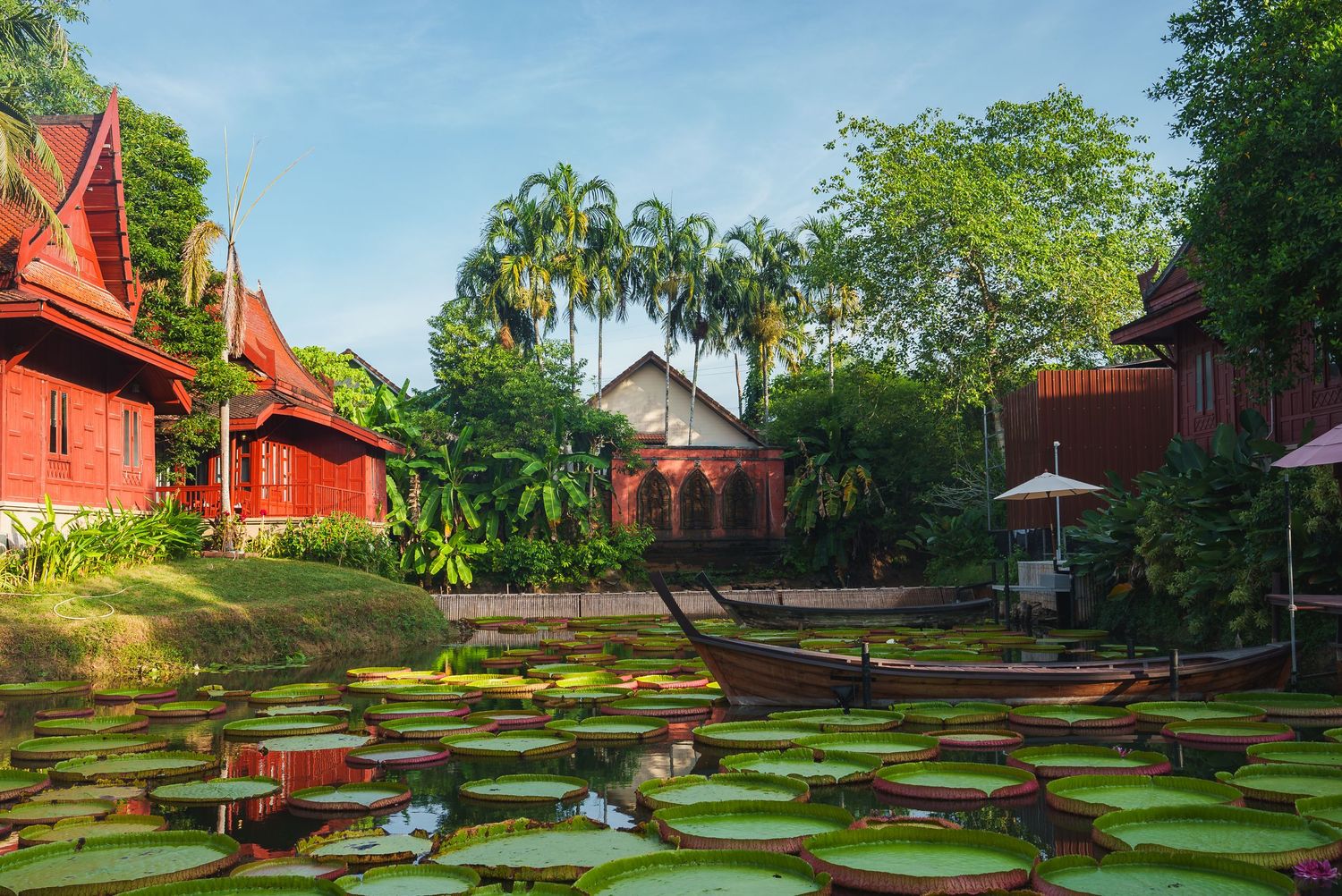 Red historic buildings arranged on terraced green lawns under blue sky.