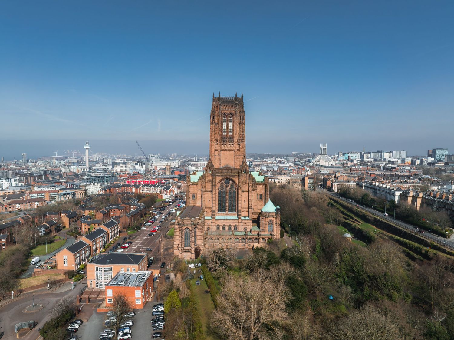 Panoramic cityscape view with cathedral and Ferris wheel visible against clear blue sky.