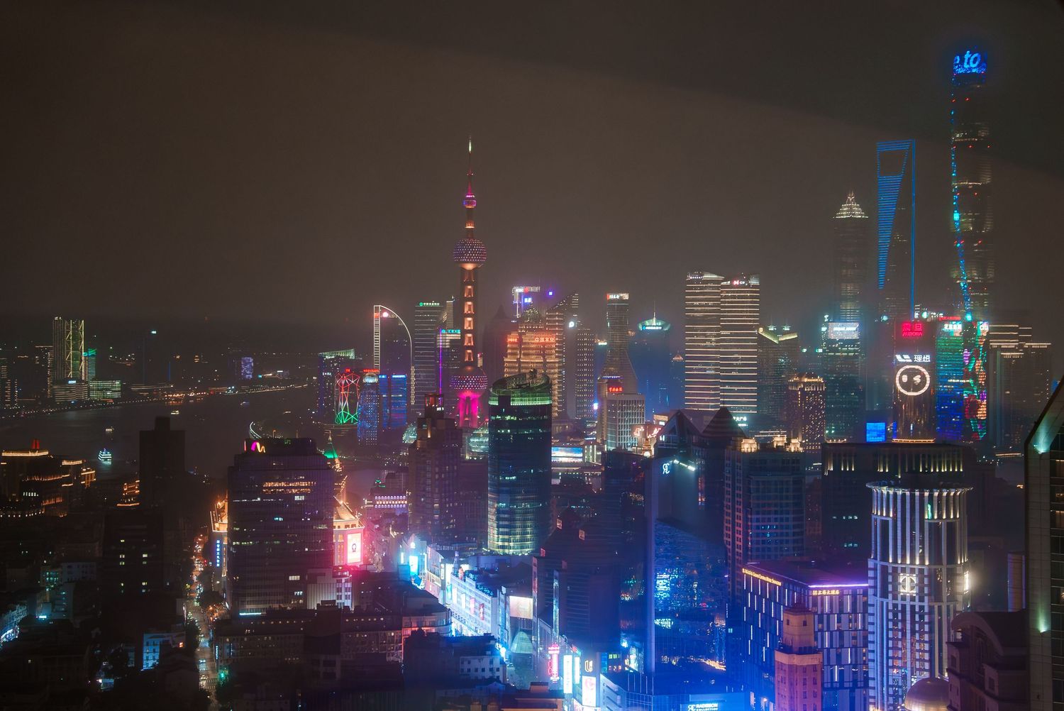 Vibrant night cityscape of Shanghai with colorful neon lights illuminating skyscrapers.