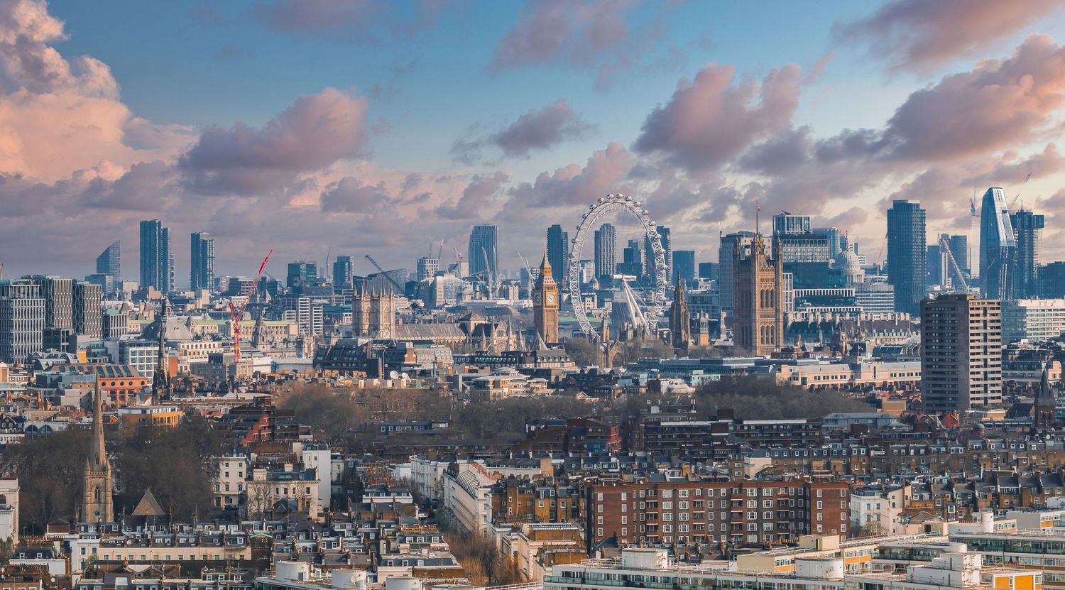 Panoramic cityscape of London's financial district with modern skyscrapers against a cloudy sky.