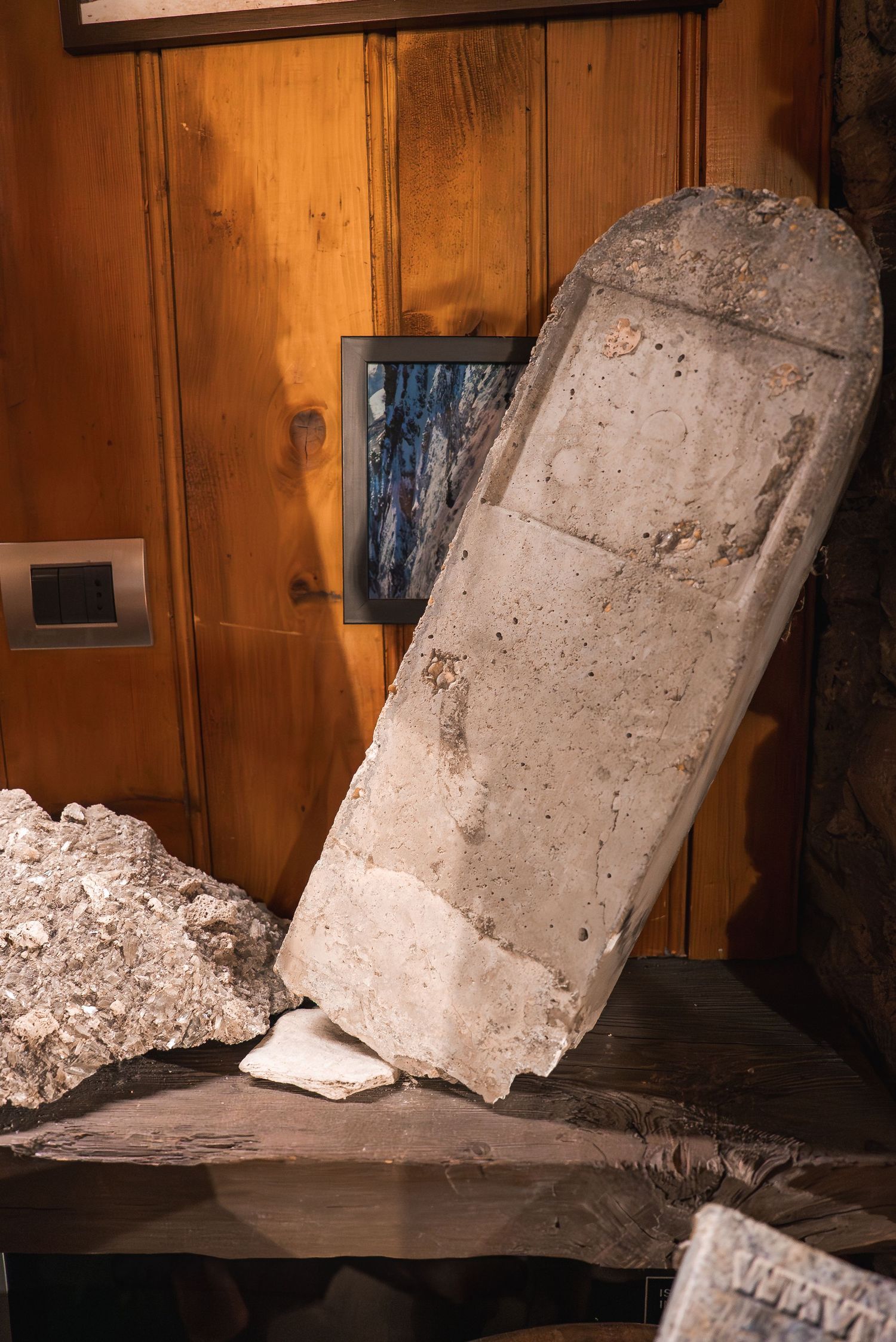 Concrete blocks leaning against wooden paneled walls in a dimly lit interior space.