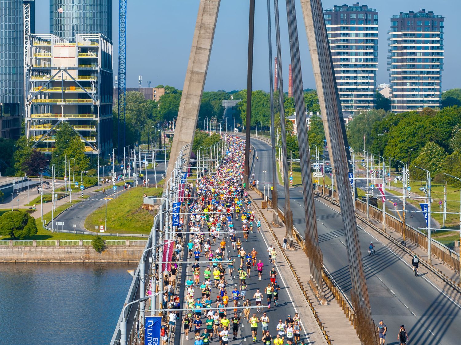 Panoramic view of a bridge filled with marathon runners against a city skyline.