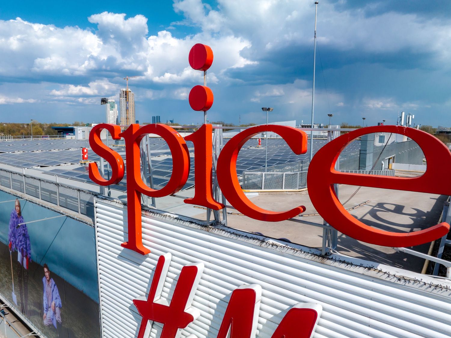 Large red Spice lettering mounted on white corrugated building facade with red balloons.