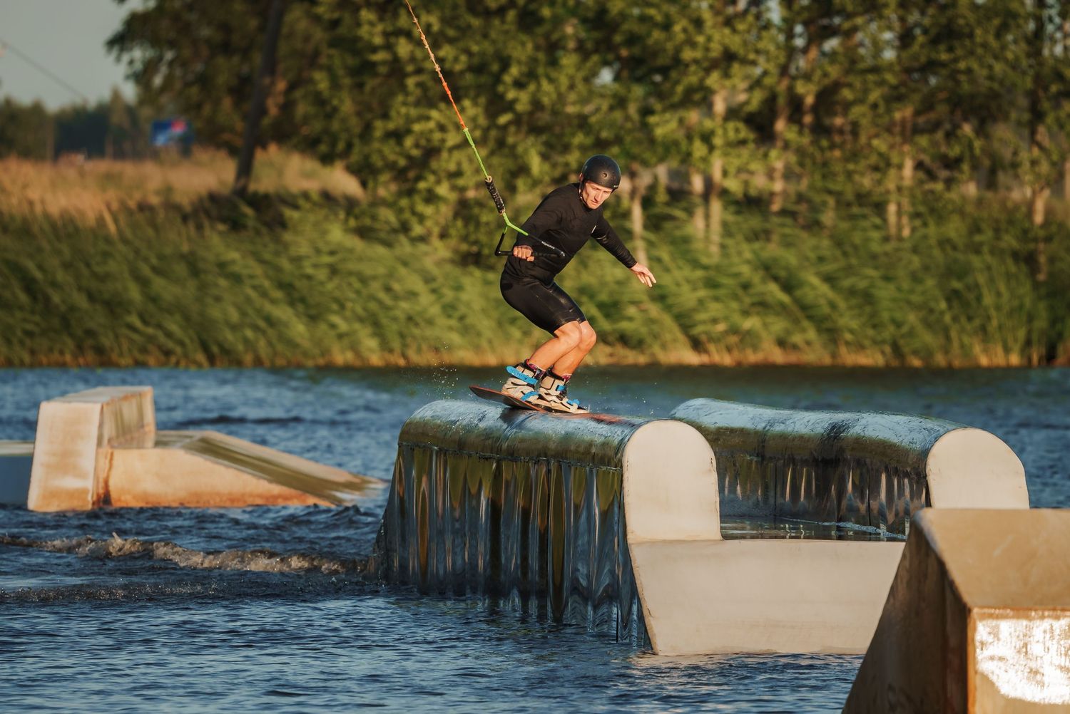 Wakeboarding action shot with water splash against concrete ramp on a lake.