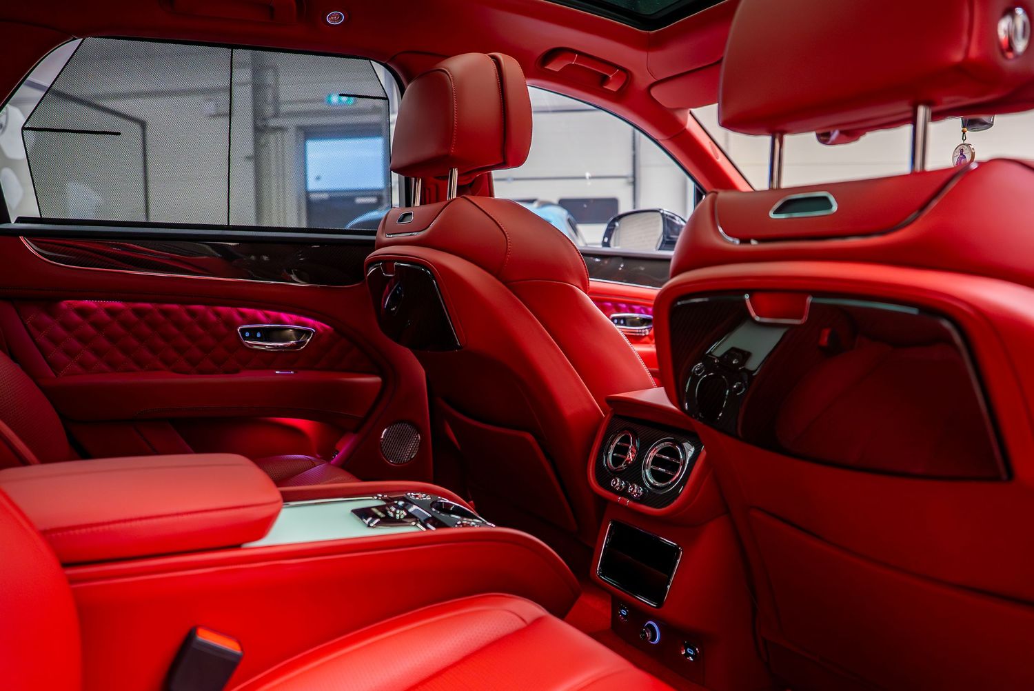Luxurious red leather interior of a Bentley showing premium craftsmanship and design details.