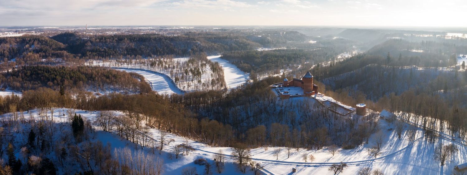 Aerial panoramic winter view of a snow-covered mountain resort with ski slopes and lifts stretching across the landscape.