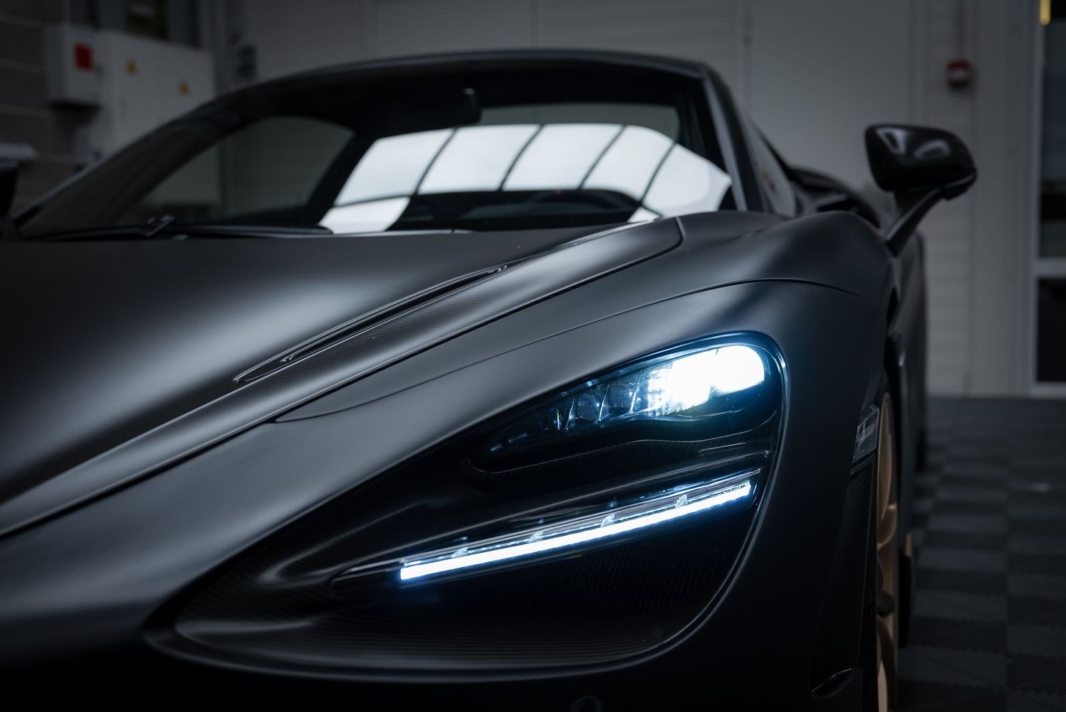 Detailed view of McLaren supercar LED headlight with distinctive blue lighting signature.