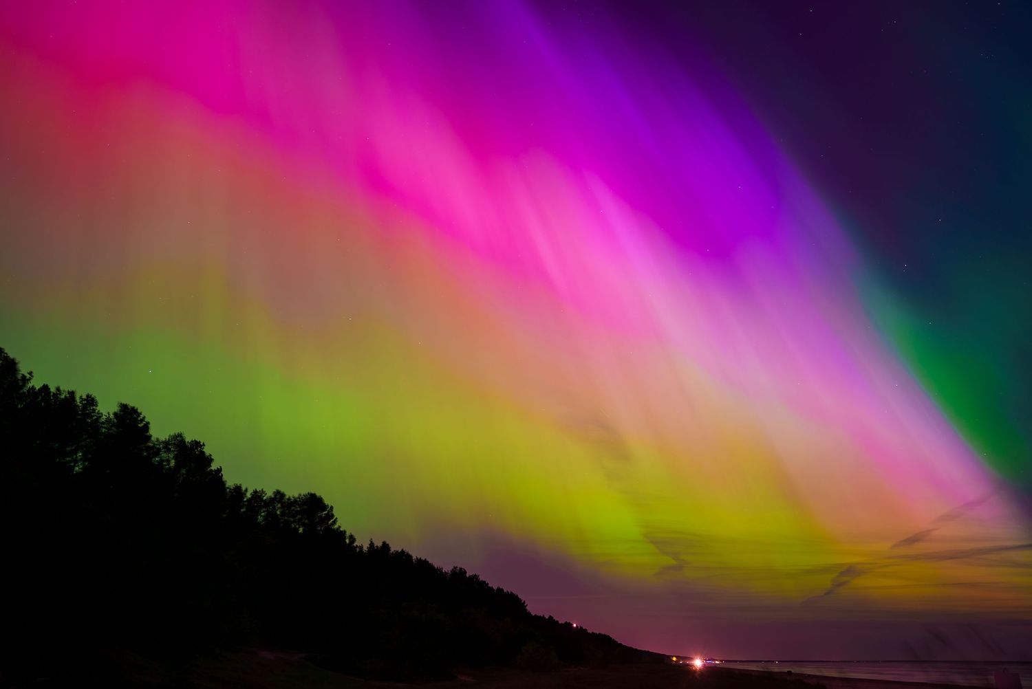 Colorful aurora borealis displays pink and purple hues across the night sky.