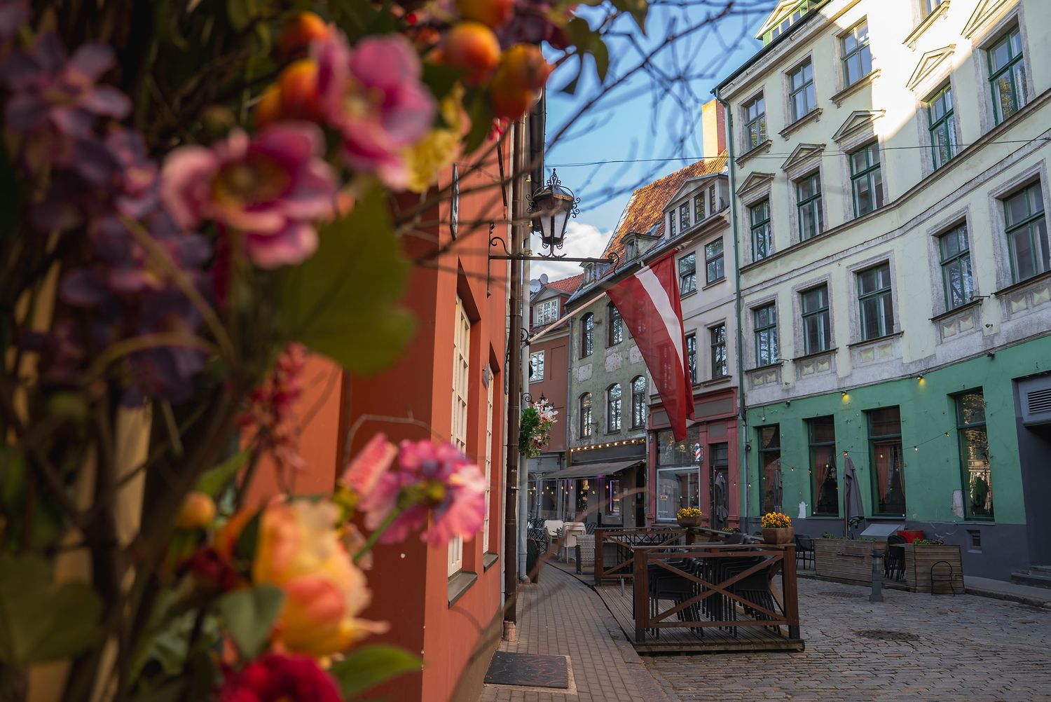 Charming European cobblestone street with colorful historic buildings and spring blossoms.