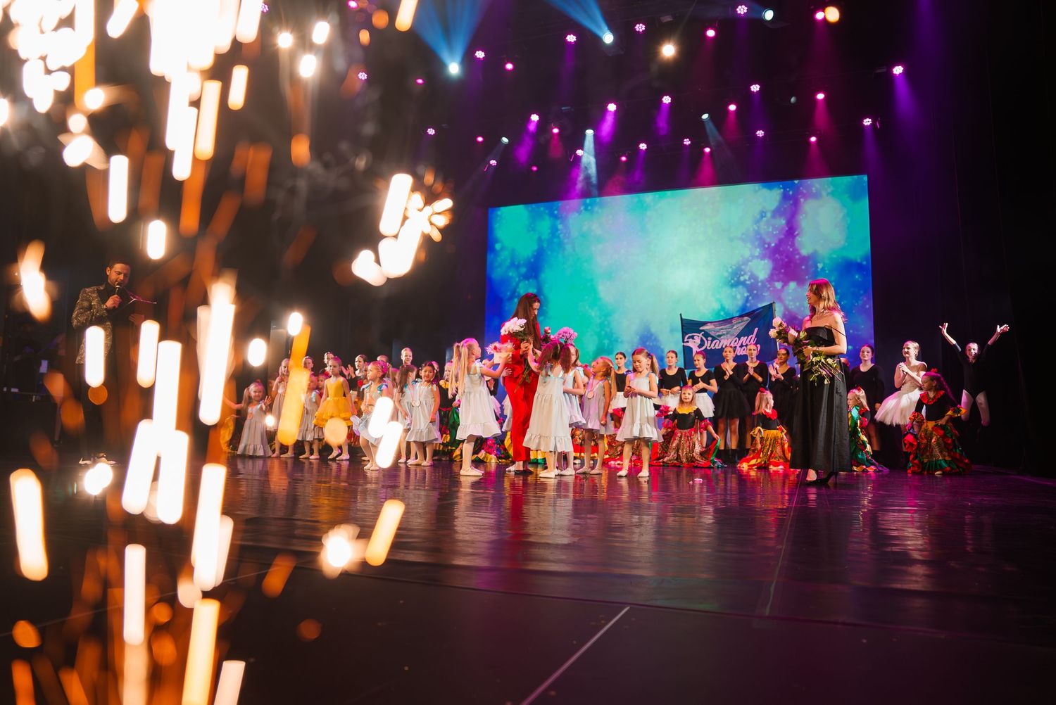 Stage performance with purple and blue lighting creates a mystical atmosphere during a dance recital.