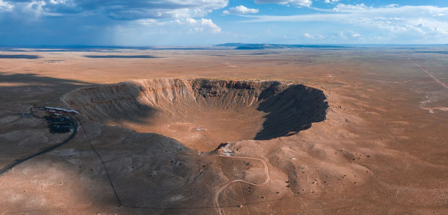 Aerial view of a massive impact crater in a desert landscape under blue skies.