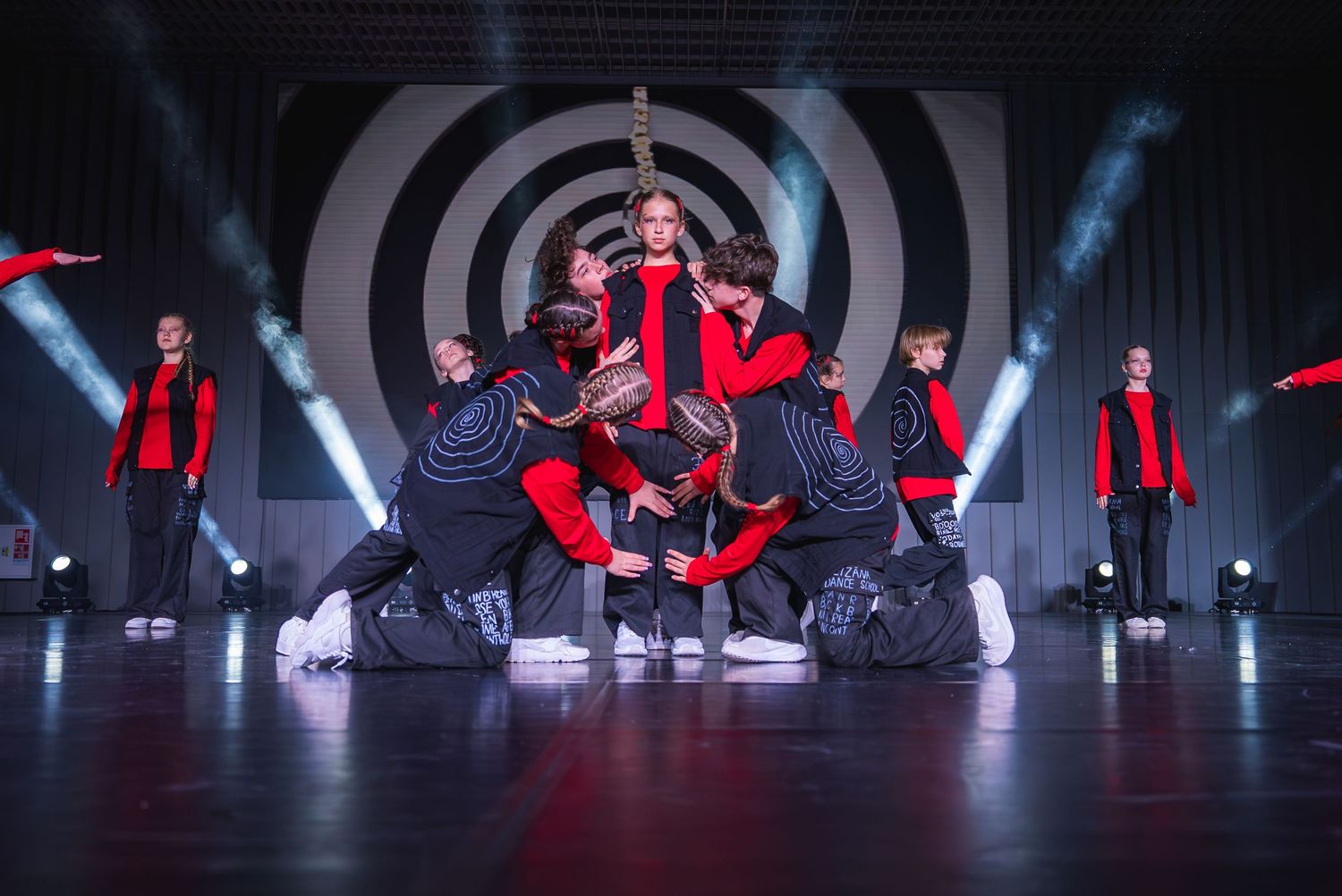 Dynamic dance routine with performers in red costumes against a geometric backdrop.