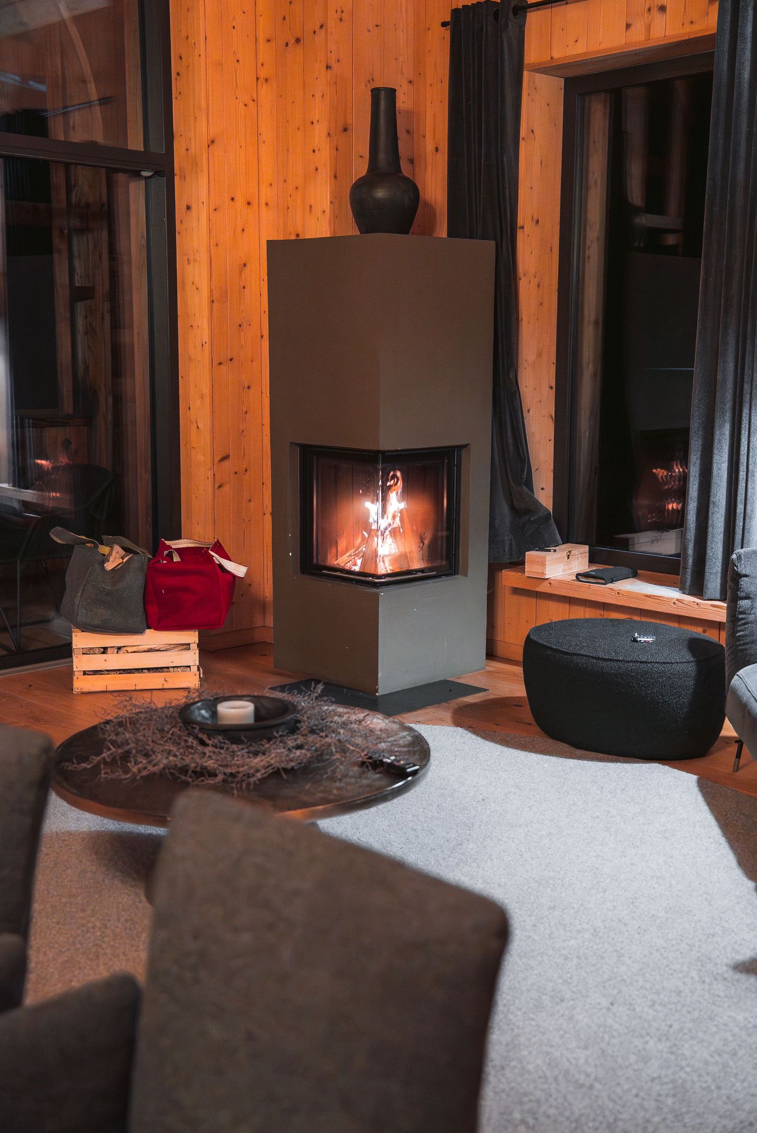 Cozy modern cabin interior with wooden walls and fireplace creating warm ambient lighting.