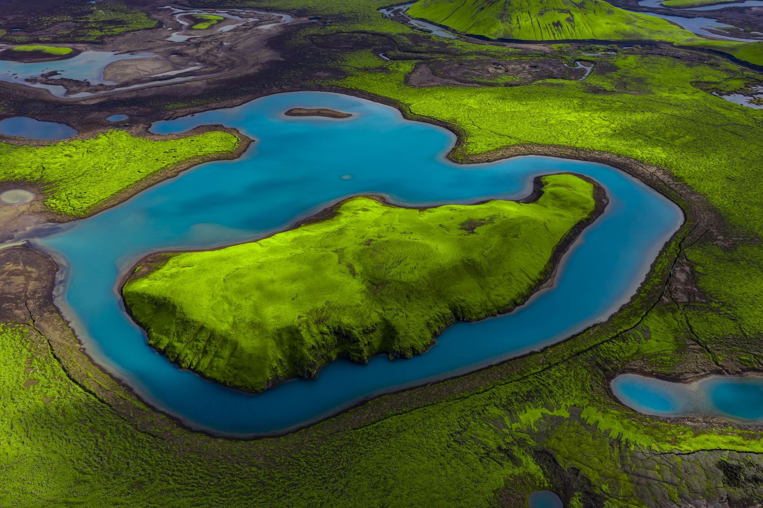 Aerial view of vibrant green wetlands with winding turquoise river channels creating a stunning natural pattern.