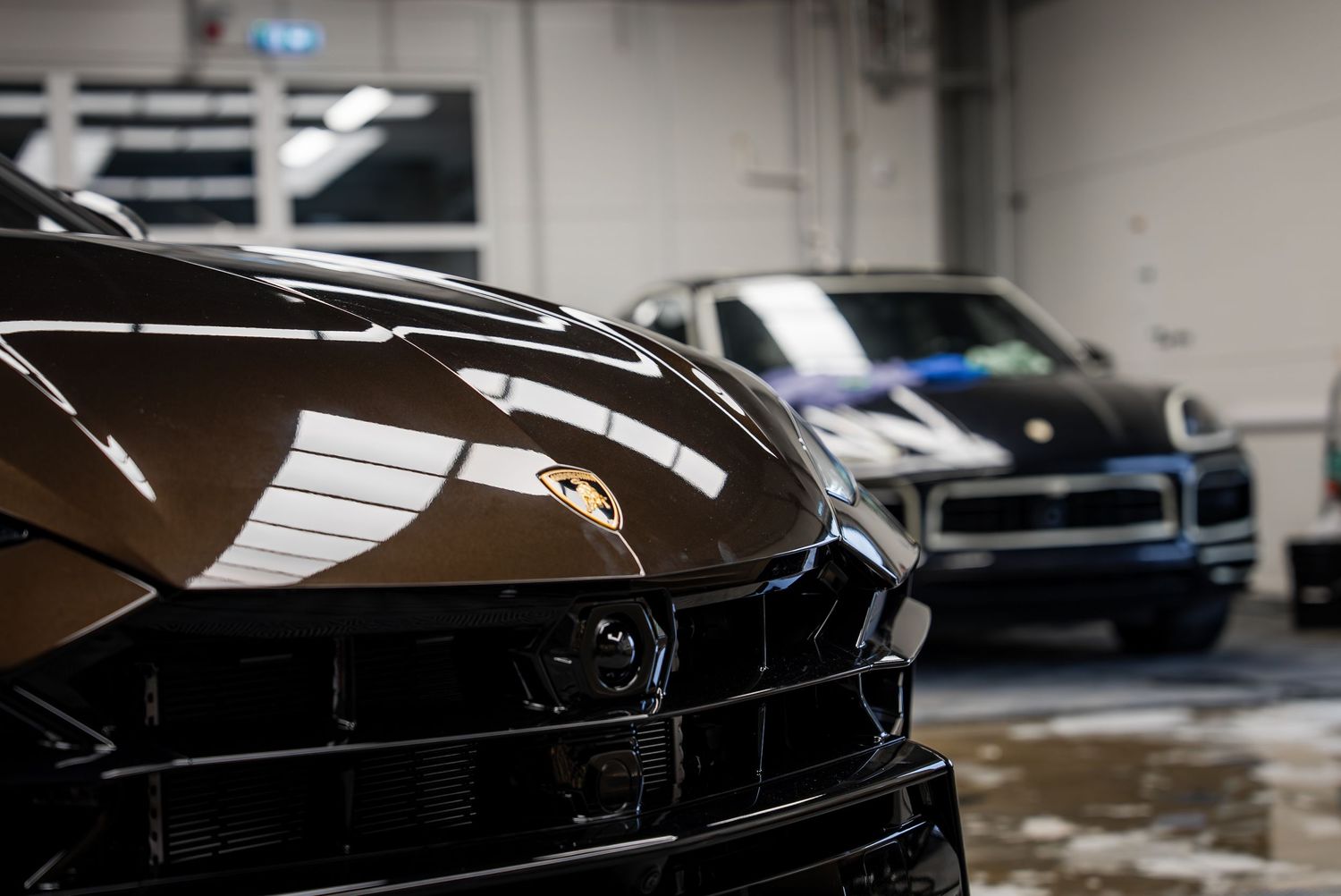 Close-up of luxury sports car front end with another vehicle visible in background.