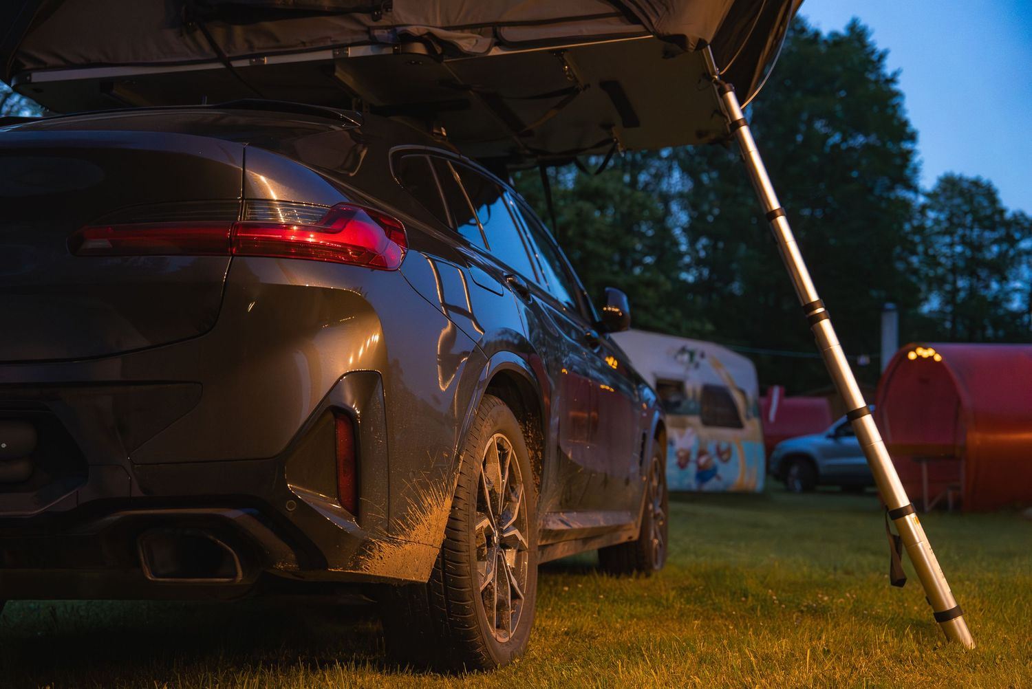 Vehicle-mounted rooftop tent setup shown at golden hour in camping area.