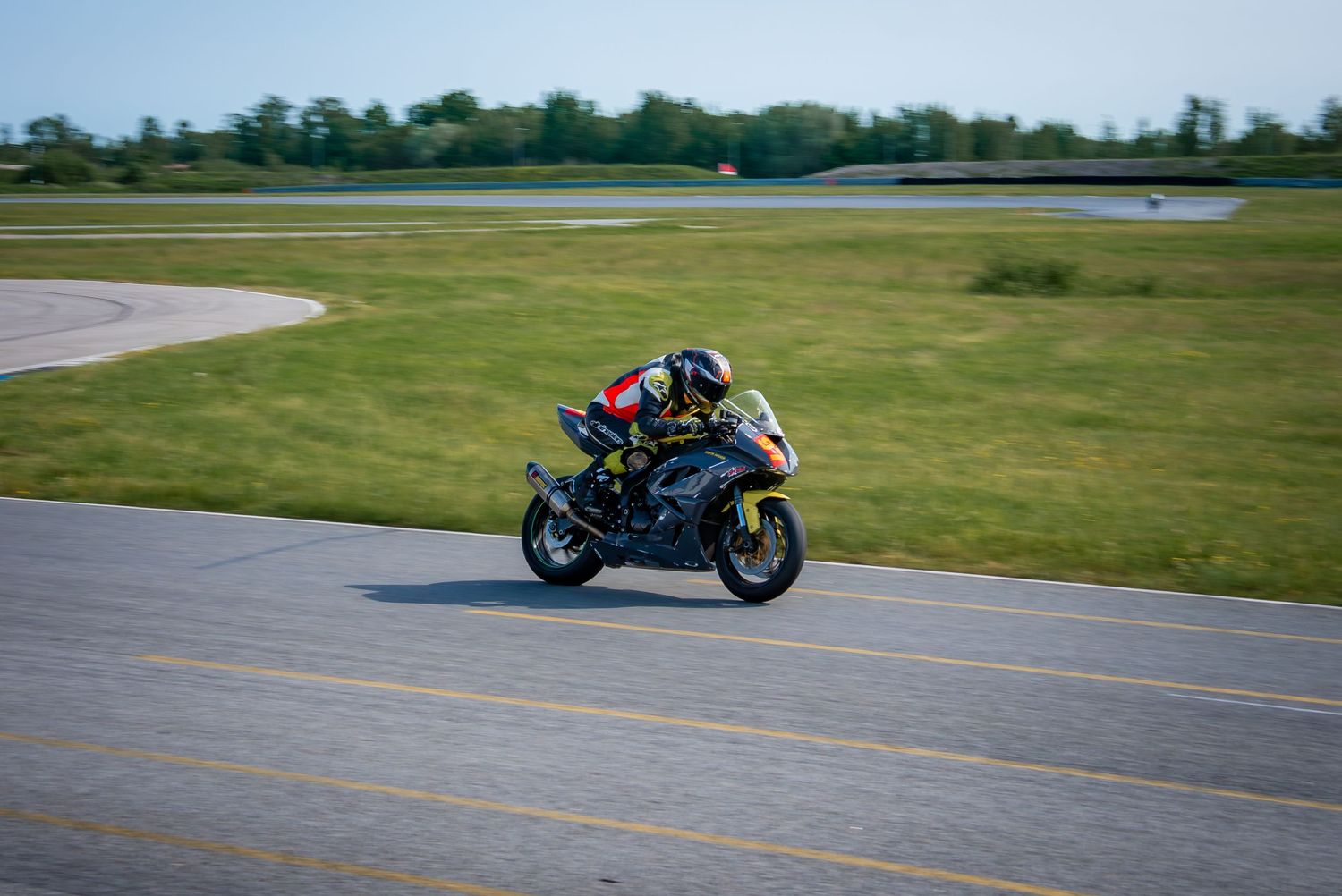 Sport bike rider racing around a curve on an empty racetrack.