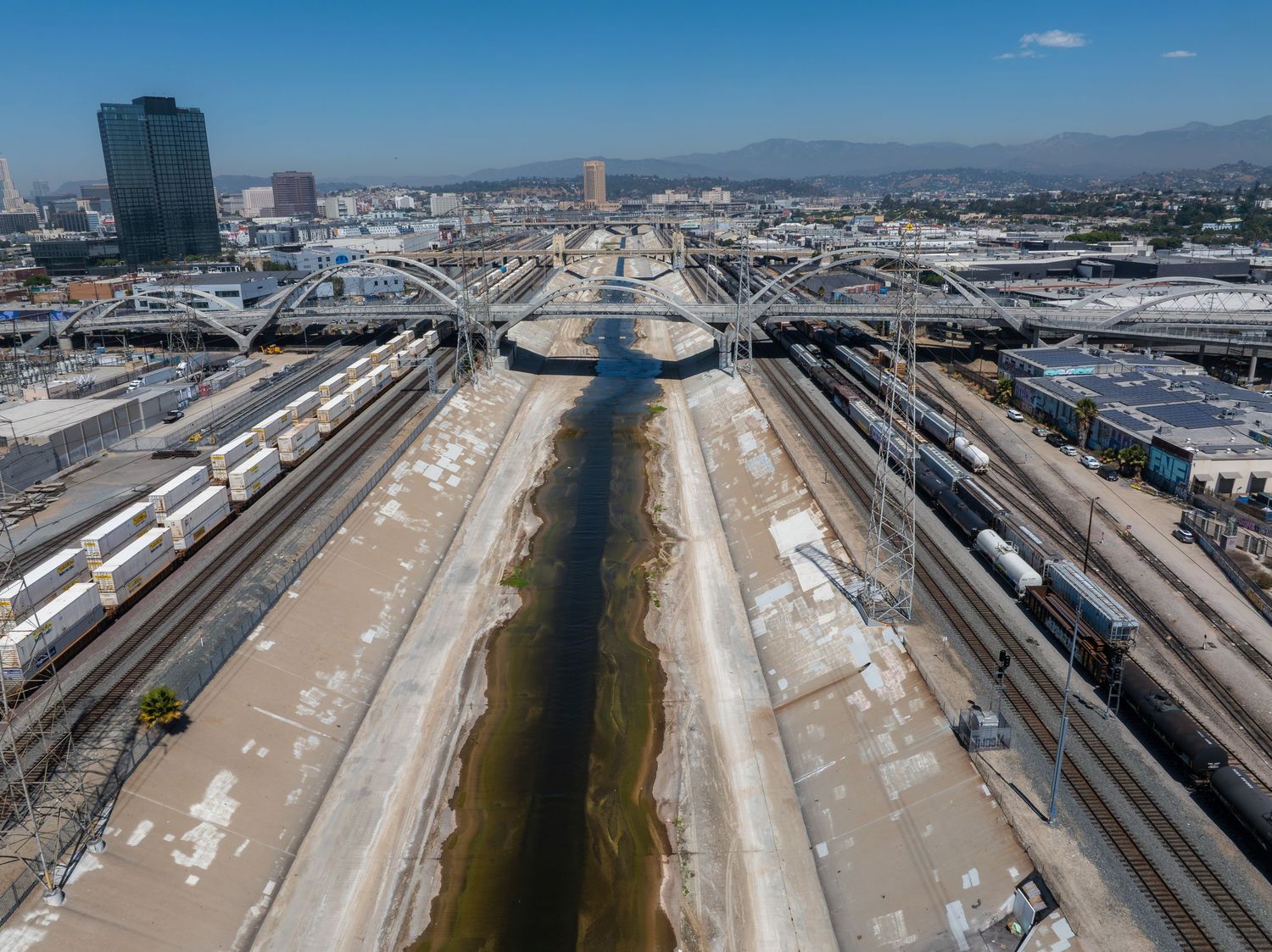 Aerial view of railway tracks and train yards stretching into the distance under blue sky.