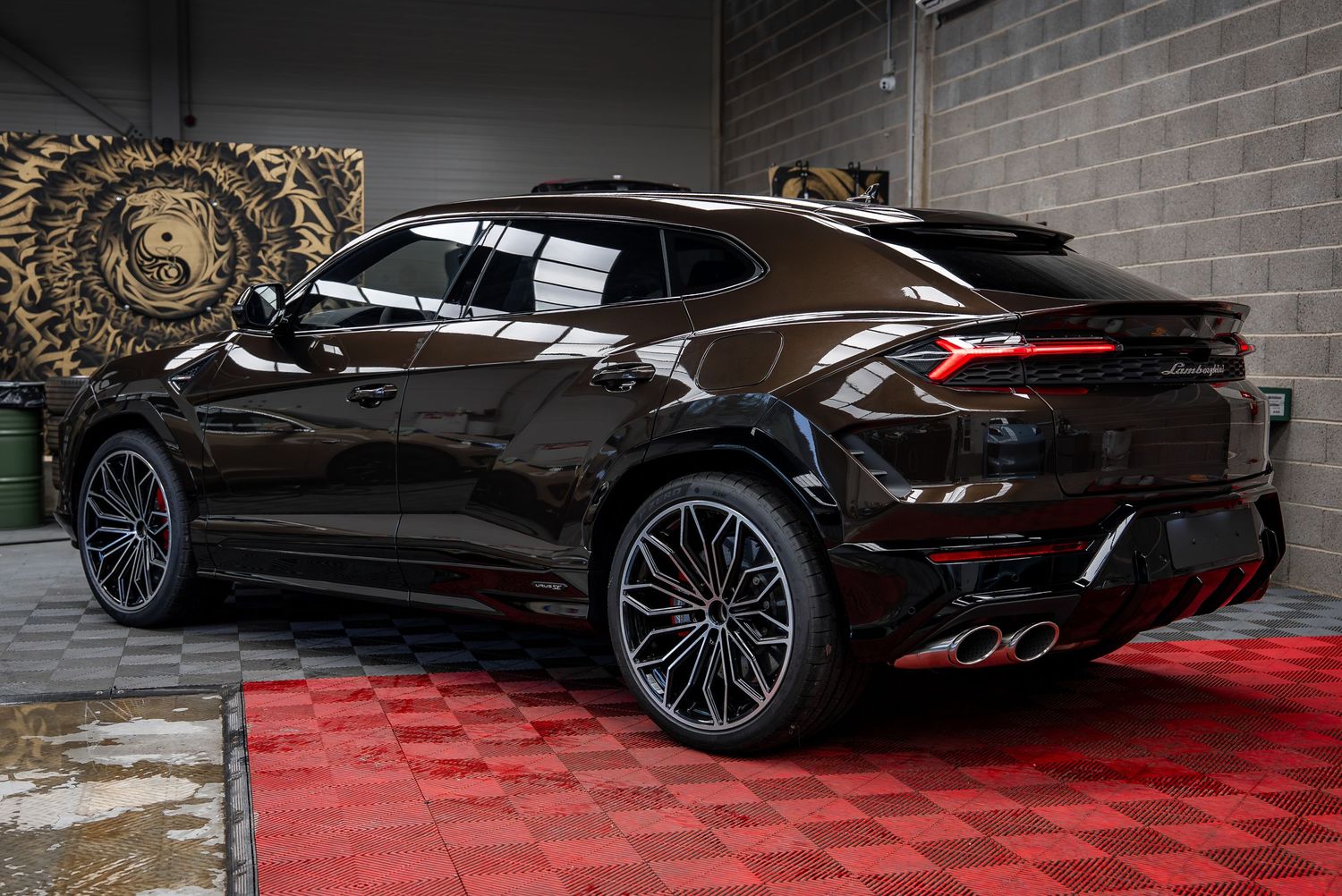 Black Lamborghini Urus SUV with custom wheels parked on red and black checkered flooring.