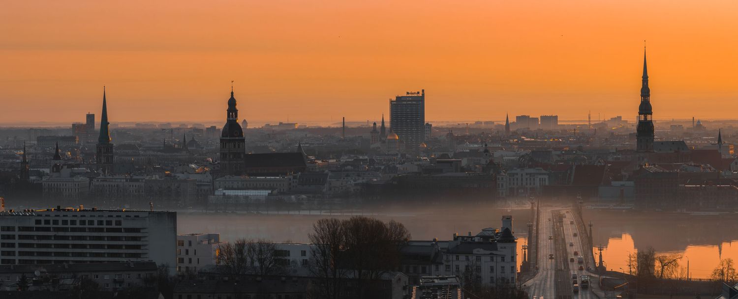 Urban skyline silhouetted against a vibrant orange sunset with architectural landmarks.