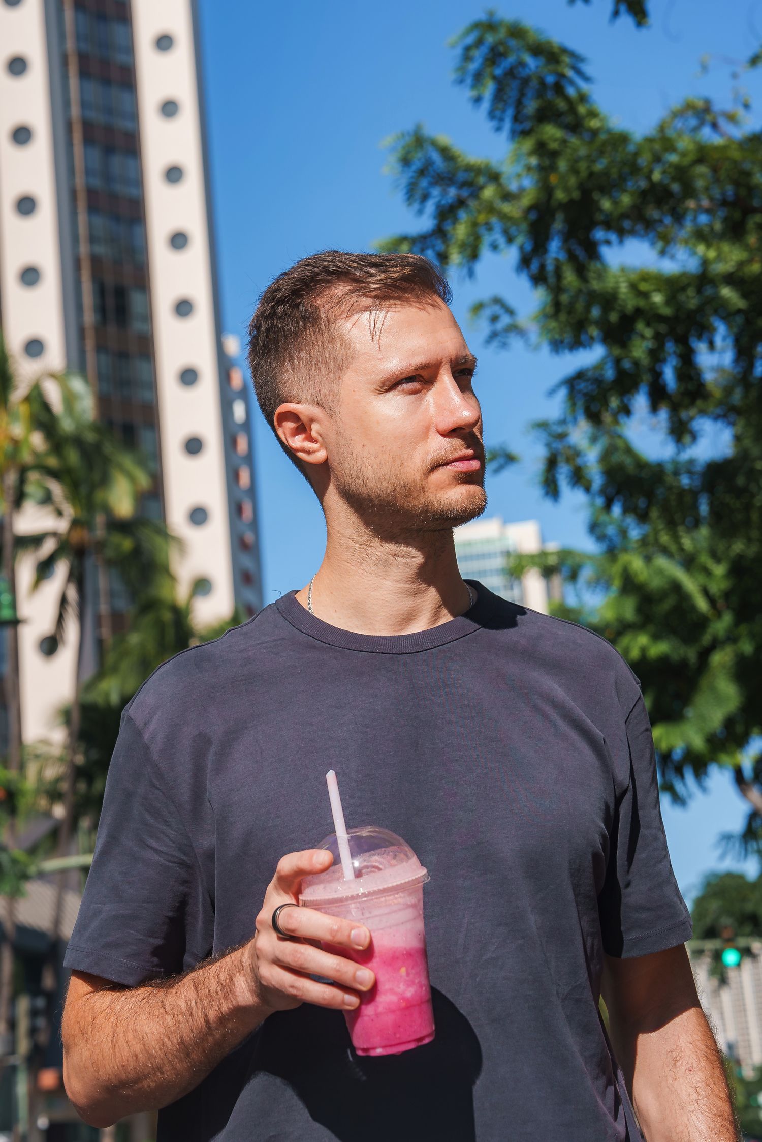 Person enjoying a pink smoothie drink on a sunny tropical day.