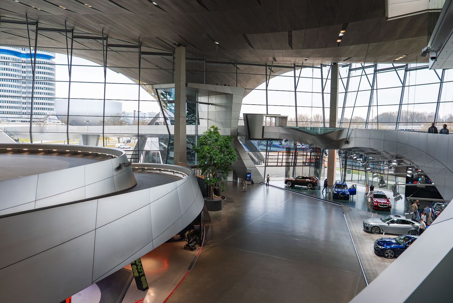 Wide panoramic view of a modern automotive museum's curved architecture and displays.