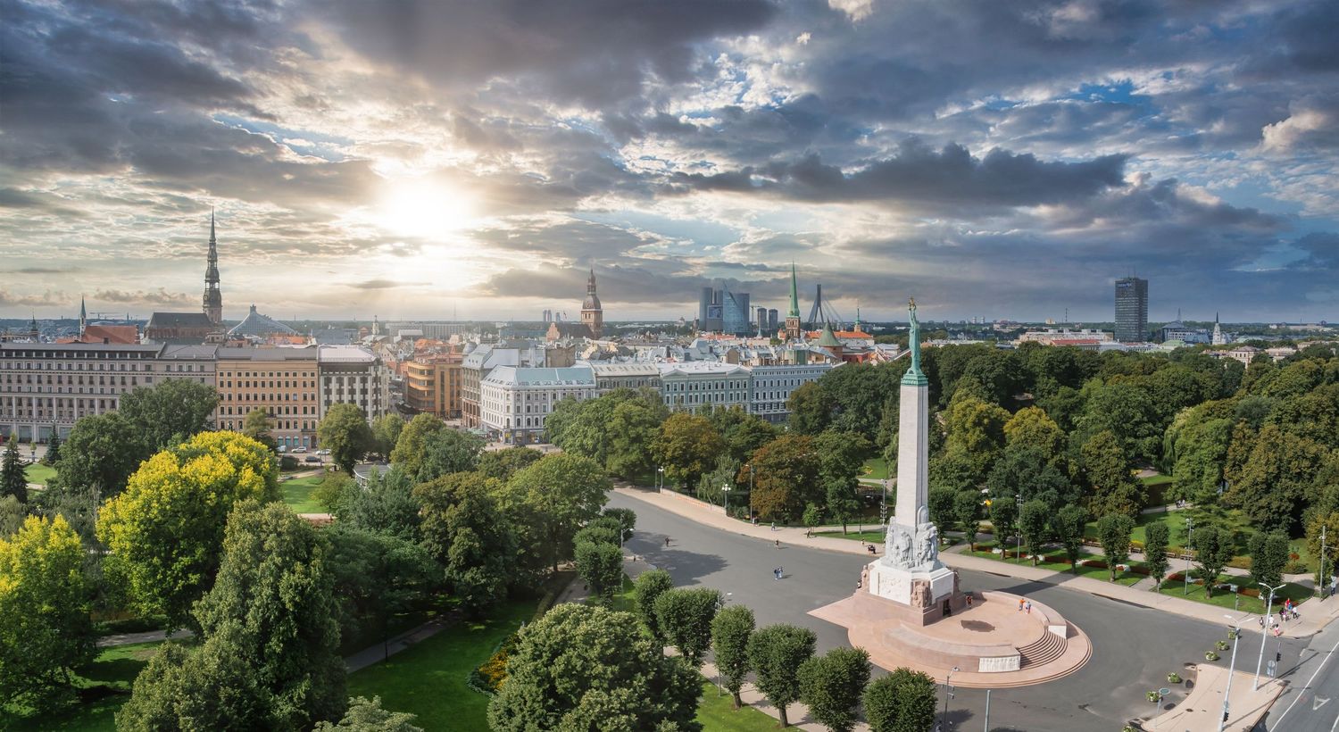 Aerial panorama of a European city with historic architecture under dramatic cloudy skies.