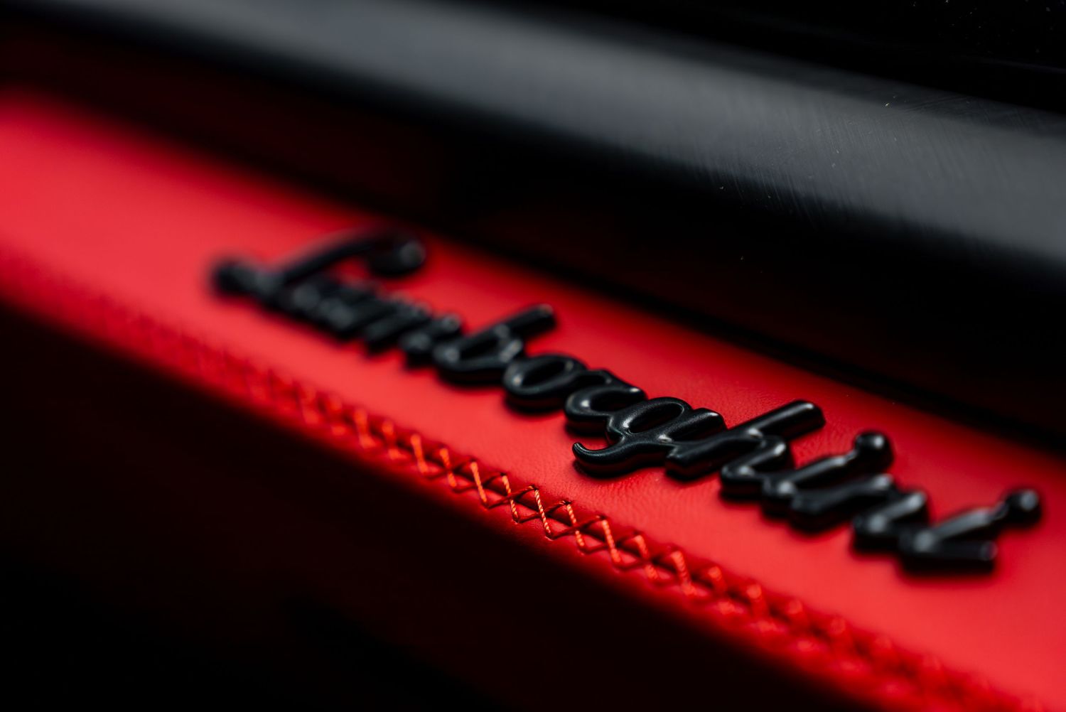 Close-up detail of red accent stitching and trim on luxury vehicle interior.