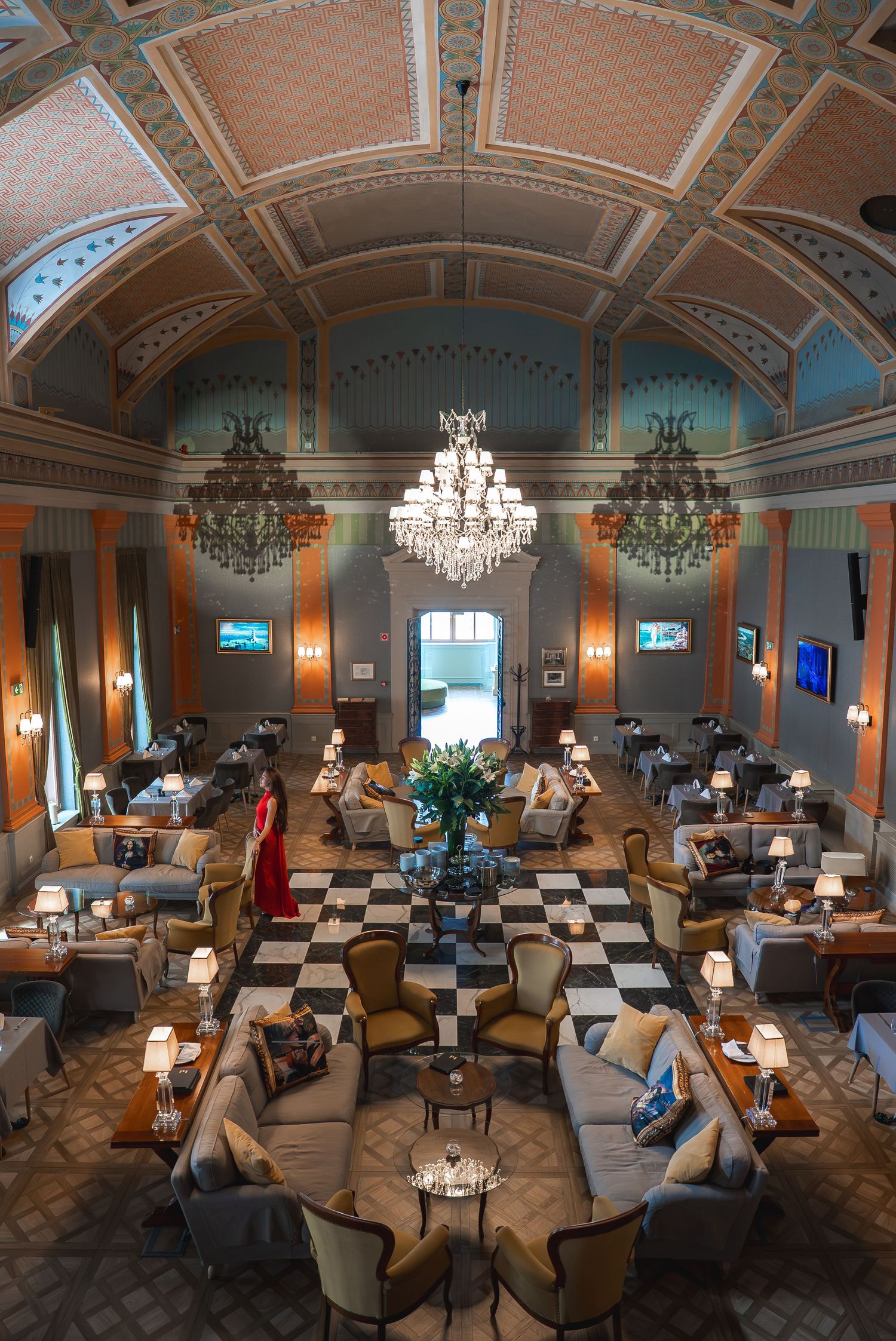 Elegant hotel lounge with ornate ceiling, crystal chandeliers and comfortable seating arrangements.