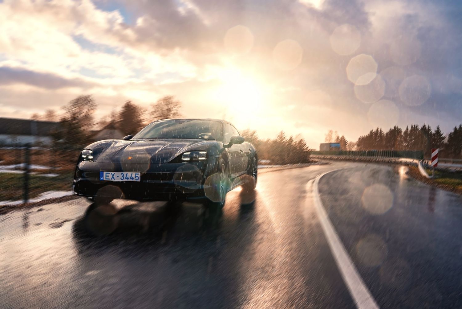 Low-angle panoramic view of Porsche Taycan with lens flare and dramatic sky.
