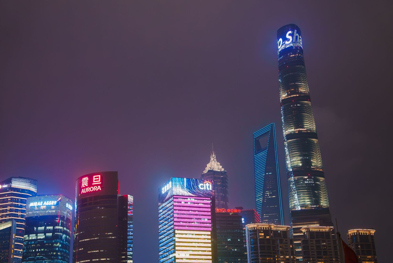 Modern city skyline with illuminated skyscrapers against dark night sky.