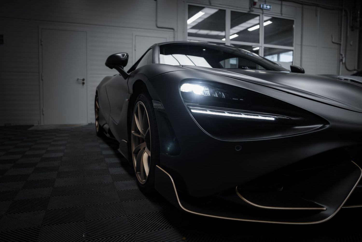 Moody low-angle photograph of a modern supercar's aggressive front design in shadows.