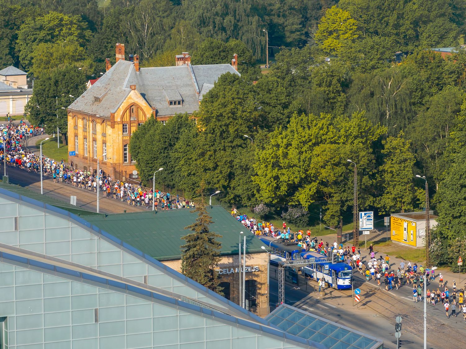 Aerial view of a sports facility surrounded by trees with crowds of spectators.