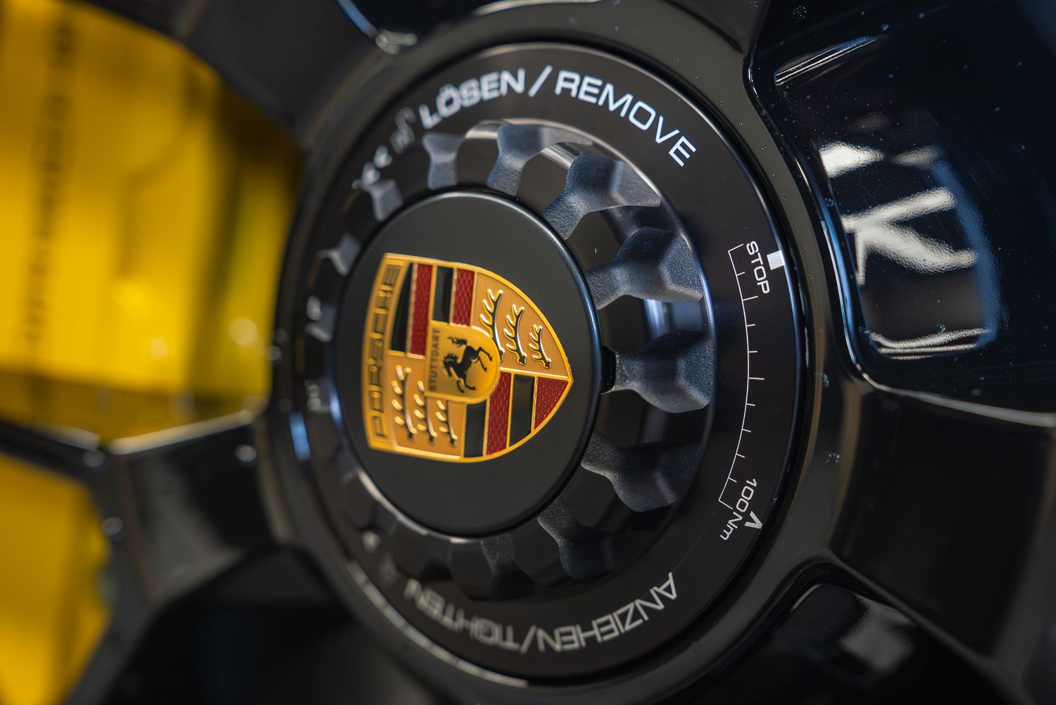 Close-up of Porsche wheel center cap with black mechanical detail.