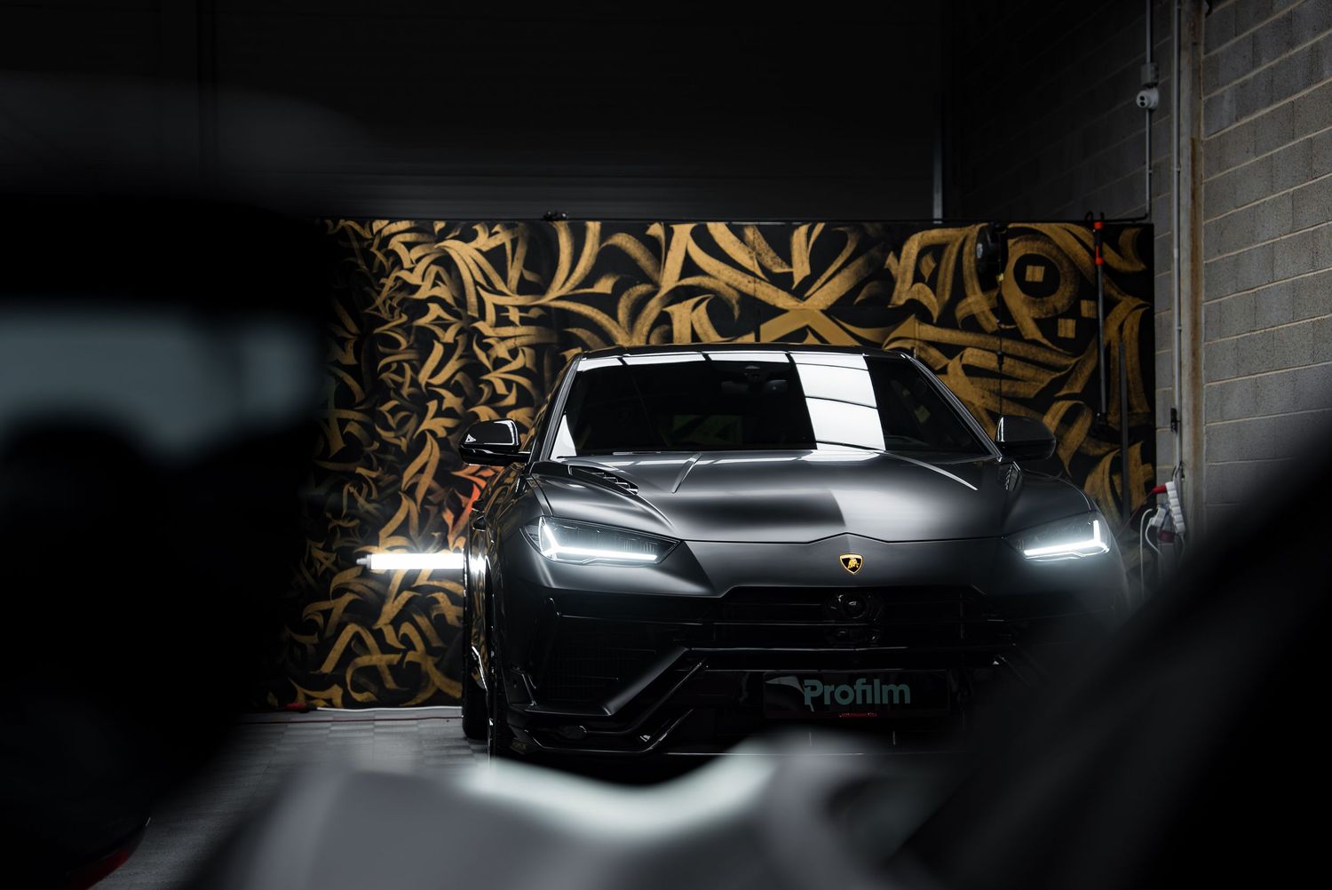 Front view of a sleek electric vehicle with illuminated headlights against an artistic backdrop.