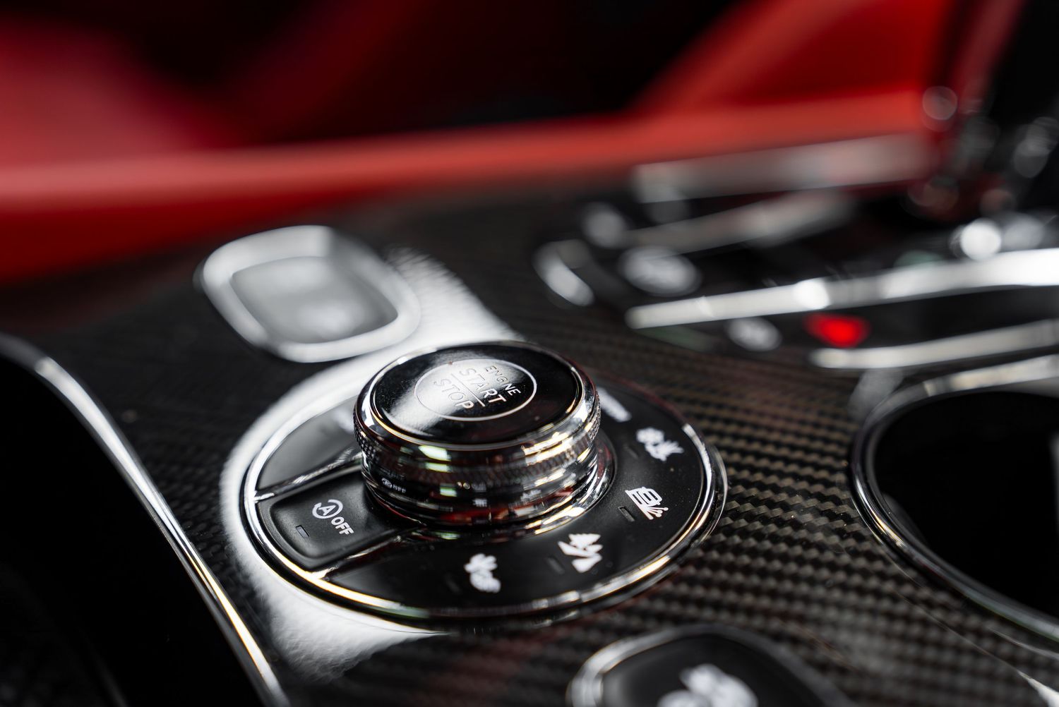 Close-up of carbon fiber and metal control knobs in a premium Bentley interior.