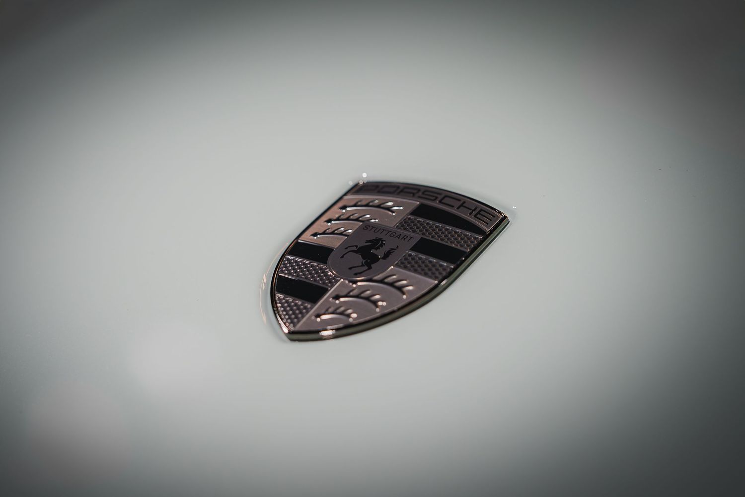 Artistic gradient shot focusing on the iconic Porsche emblem against a blurred background.