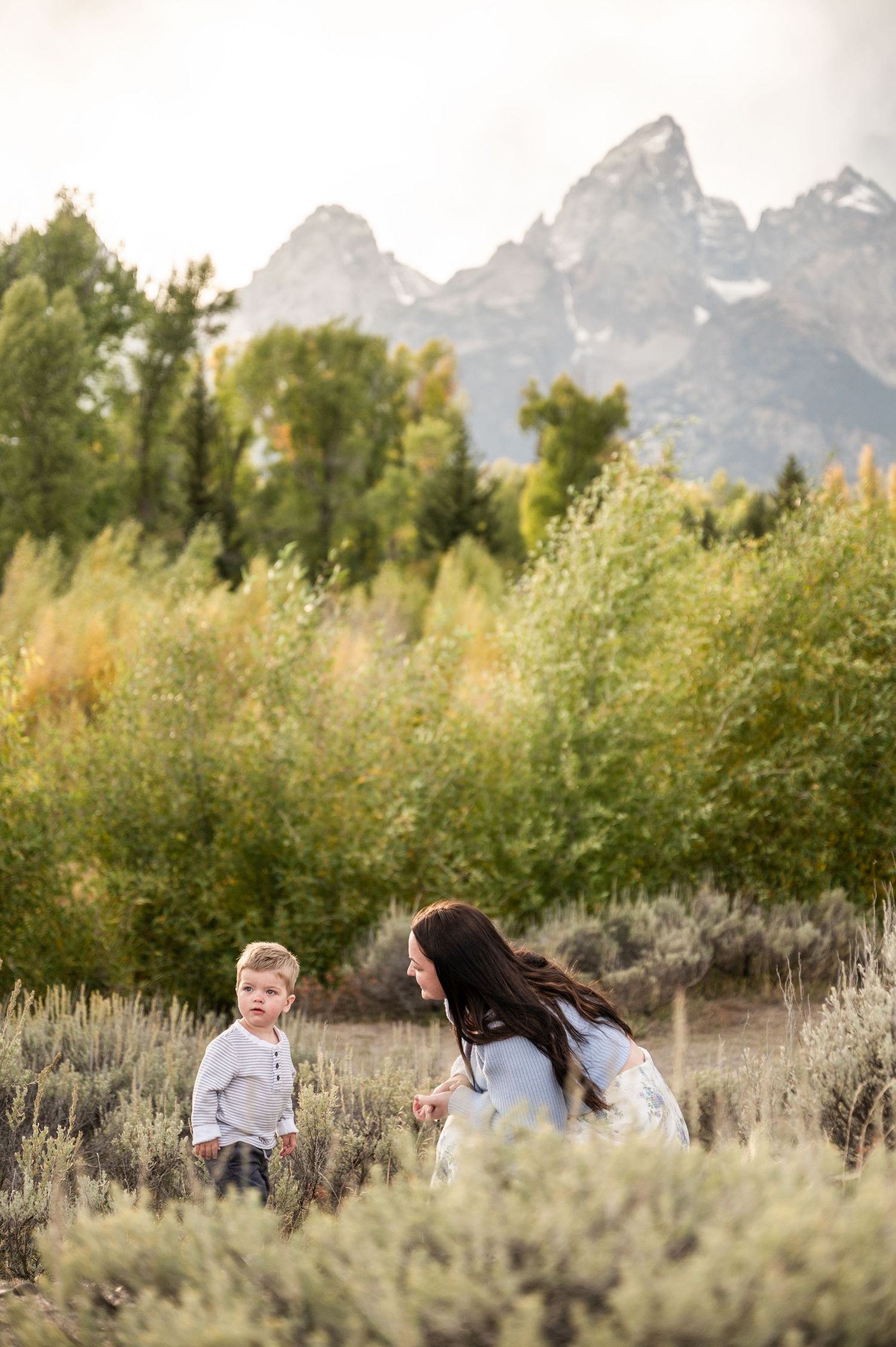 Mom and son playing in the grass with the Grand Tetons in the background.