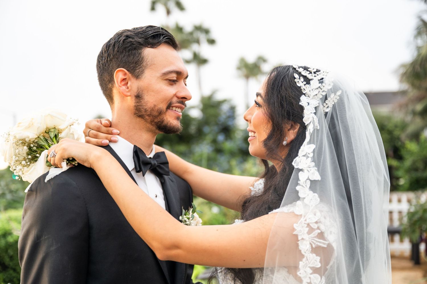 Bride and groom smiling at each other, bride’s hands around groom’s neck.