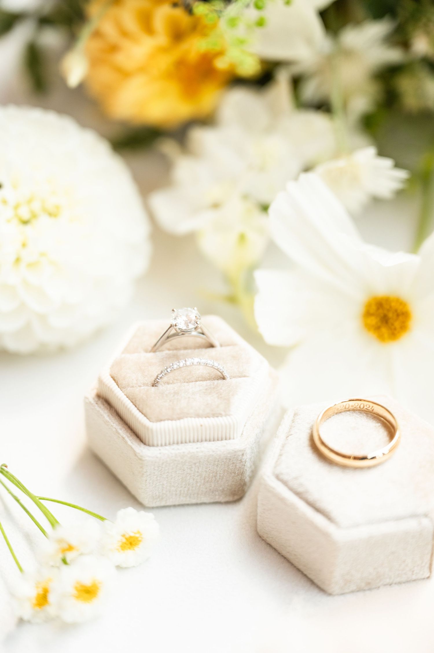 Wedding details with rings and yellow and white florals.