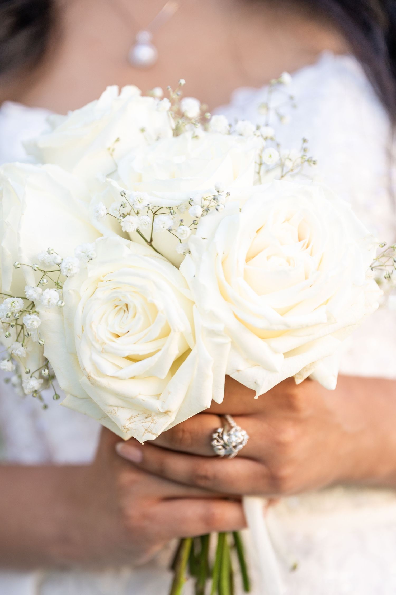 Close up of a bride and her bouquet of all white roses and baby's breath