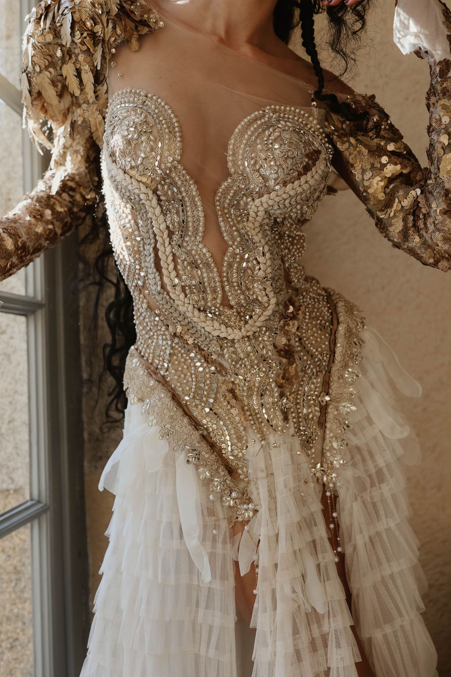 Close-up of luxurious bridal gown with pearl and sequin embroidery and ruffled skirt.