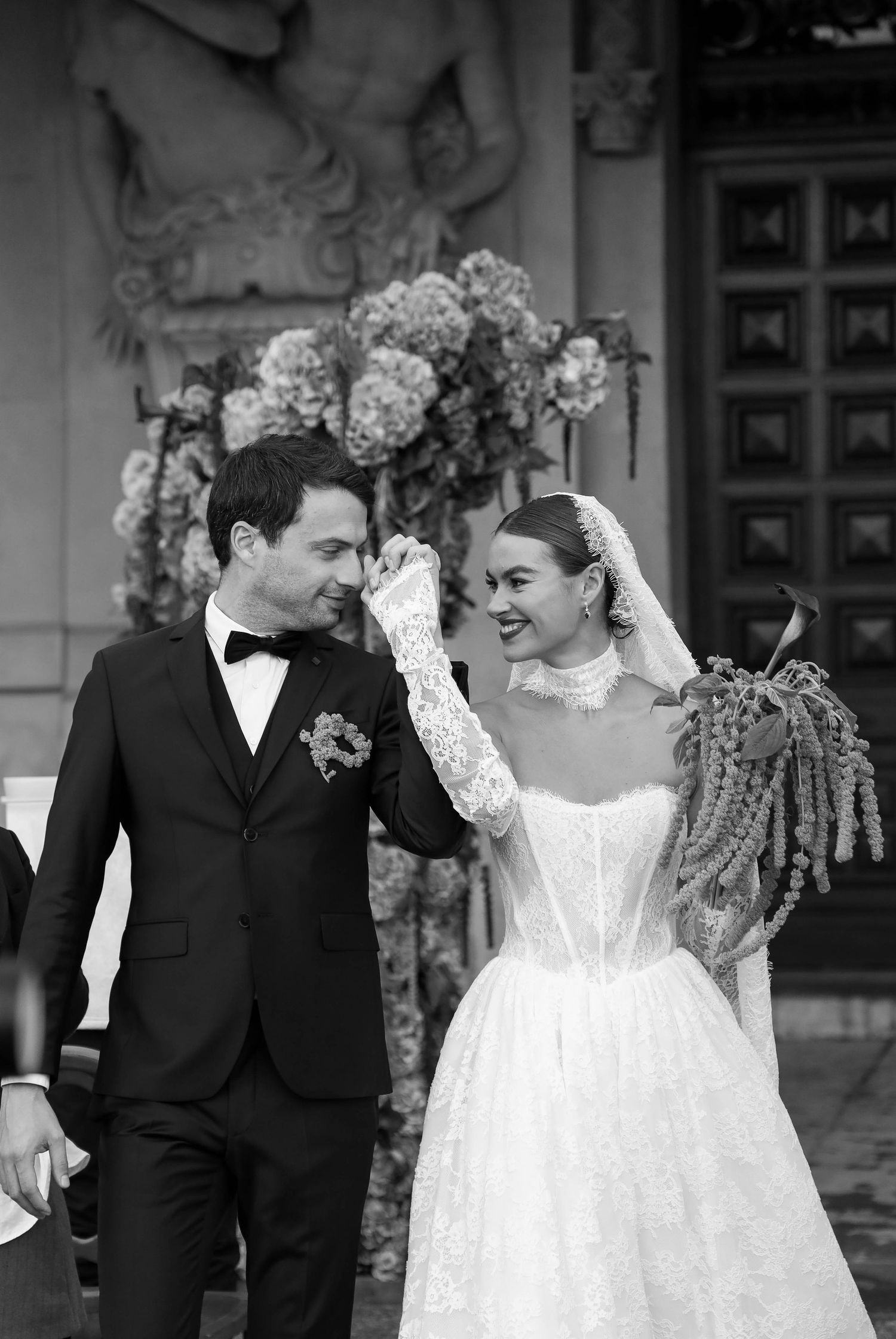 Black and white photo of bride and groom walking together after wedding ceremony outdoors.