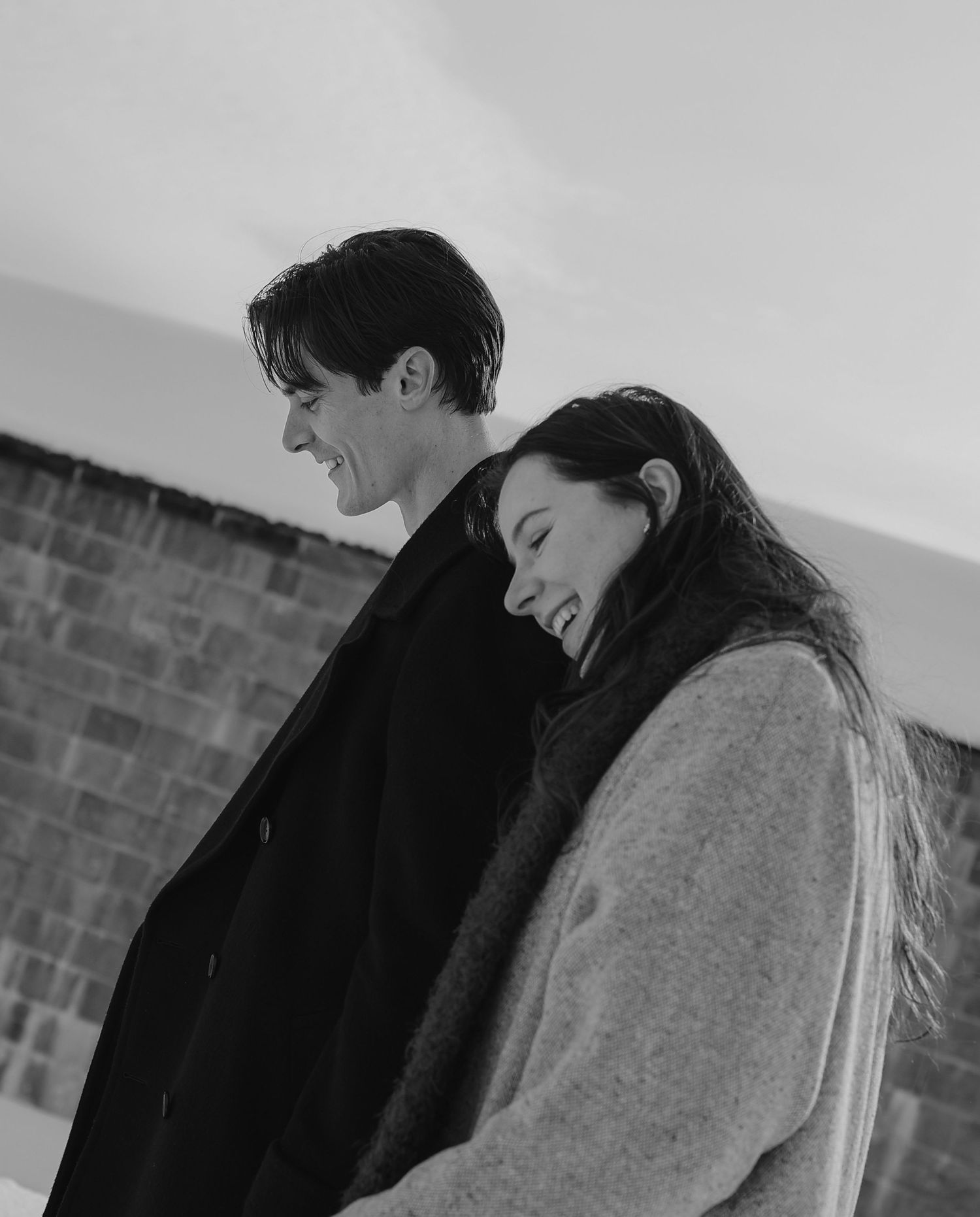 Happy couple sharing a tender moment in black and white engagement portrait outdoors.