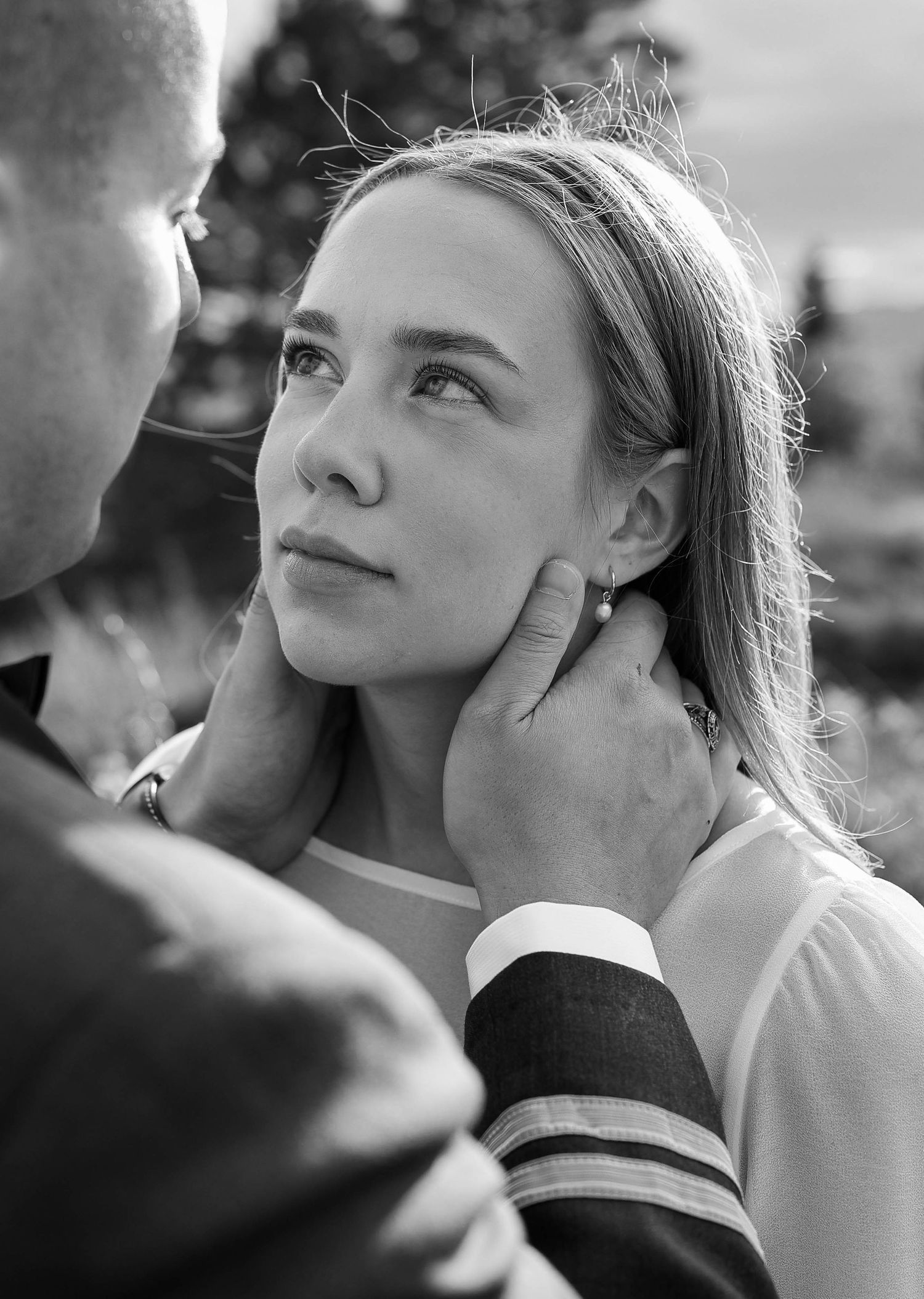 Black and white close-up of groom gently cradling brides face as she gazes up at him lovingly.